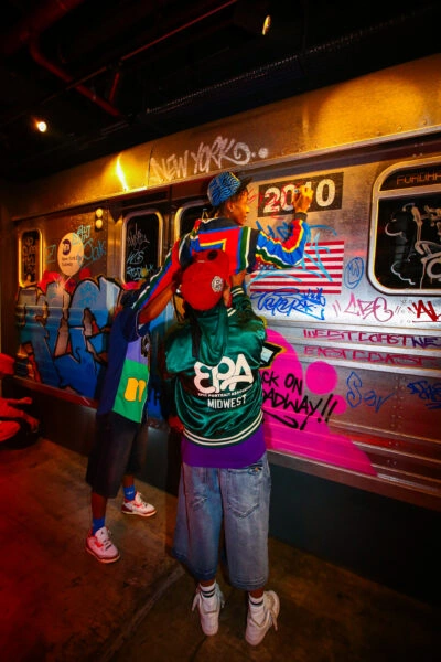 Performers beside a graffiti-covered subway carriage at the private party