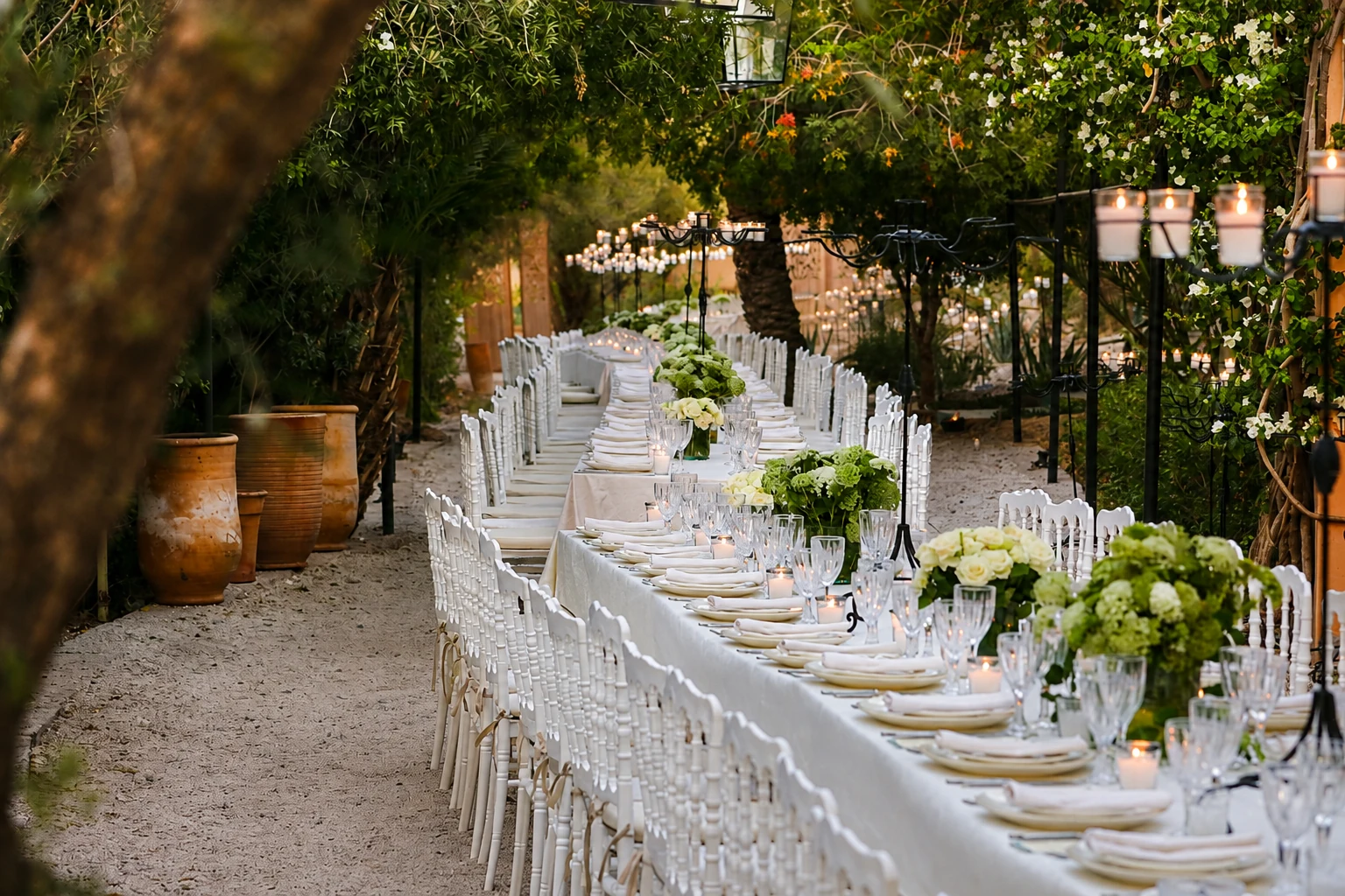 A long banqueting table with flowers and candles set under palm trees