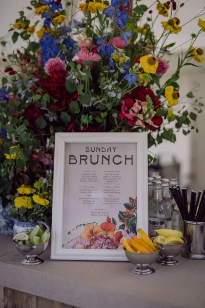 Sunday brunch menu displayed beneath colourful flowers beside bowls of fruit.